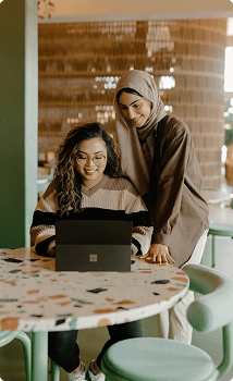 Two colleagues reviewing work on a laptop